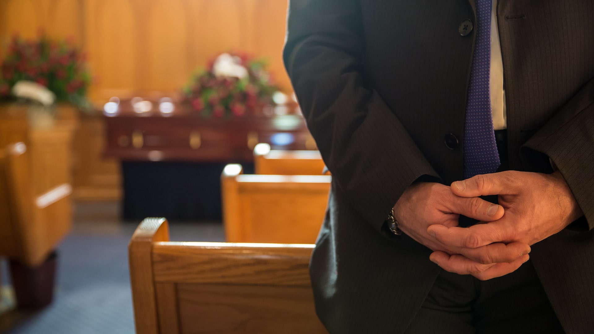 Man standing in church pews with hands at clasped
